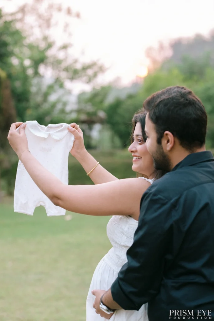 Couple holding a newborn outfit with excitement as they prepare to welcome their baby.