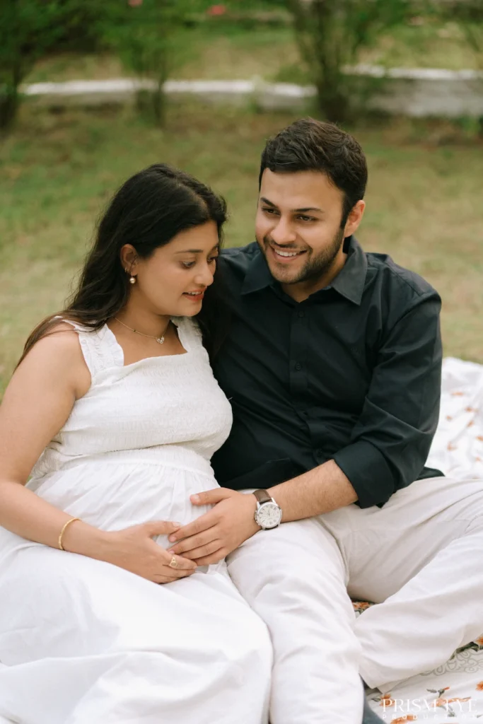 Couple relaxing on a picnic blanket while celebrating the excitement of becoming parents.