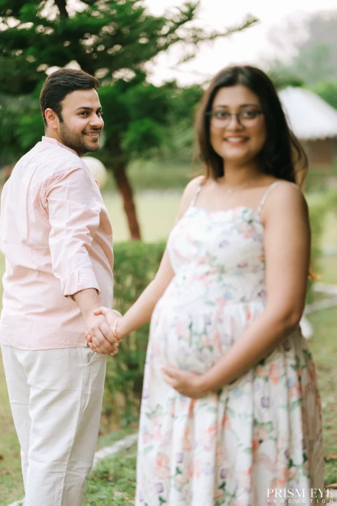 Couple holding hands during a Maternity Photoshoot, celebrating pregnancy in a beautiful outdoor