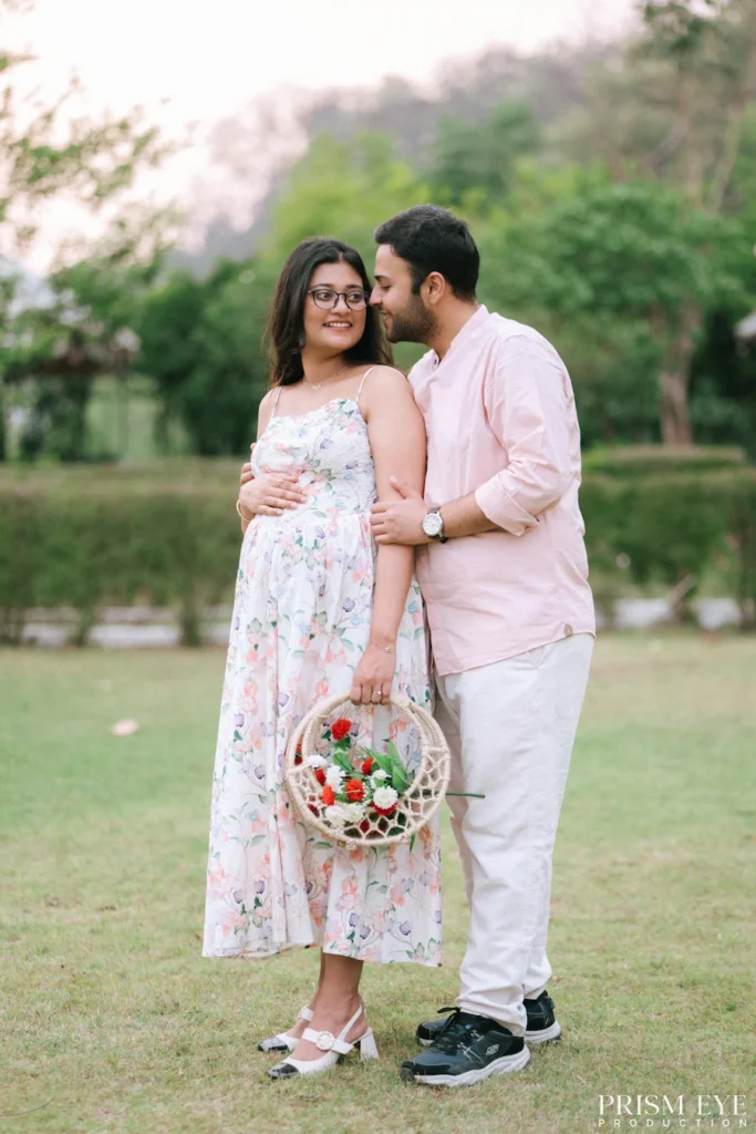 Expecting couple posing together during a Maternity Photoshoot with a floral basket in a peaceful outdoor location.