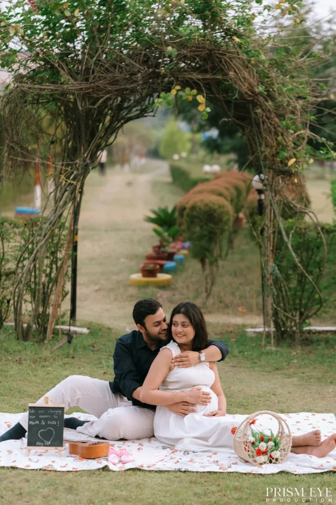 Expecting couple enjoying a peaceful picnic beneath a garden arch, capturing the joy and anticipation of welcoming their baby.