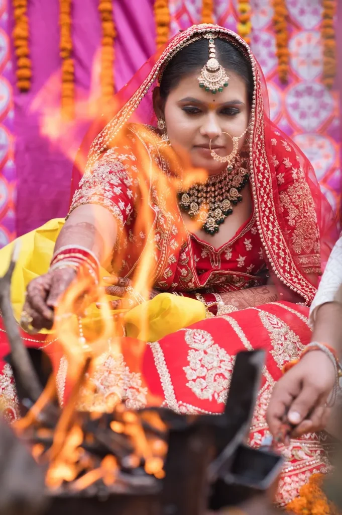 Bride performing traditional wedding rituals beside the sacred fire during the marriage ceremony.