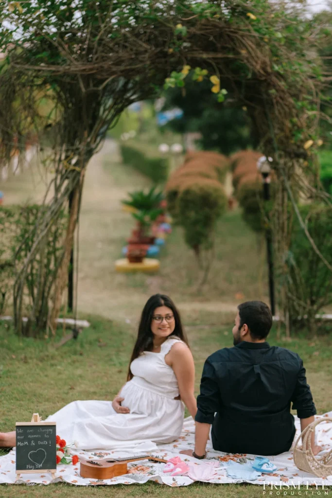 Couple sitting beneath a natural garden arch, celebrating pregnancy with love and anticipation.