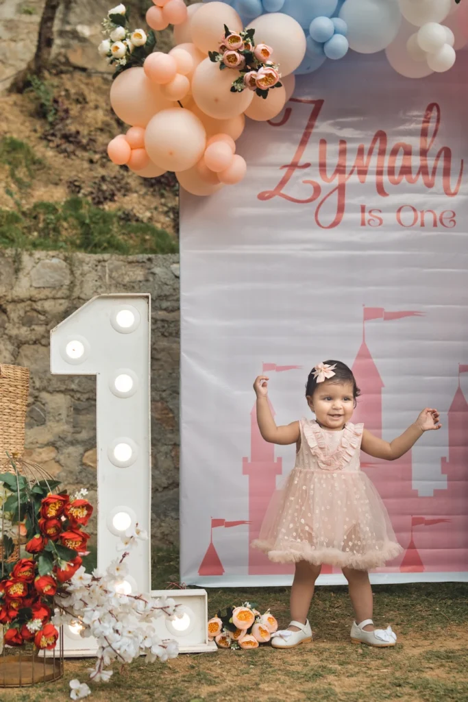 Kids Photoshoots in Dehradun capturing a little girl celebrating her first birthday with pastel balloons and a personalized backdrop.