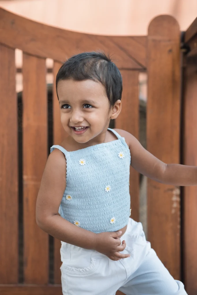 Kids Photoshoots in Dehradun featuring a smiling toddler in a blue outfit enjoying a candid outdoor portrait.