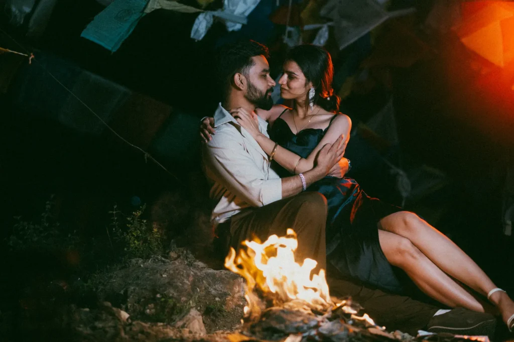 Romantic couple embracing beside a campfire during an evening outdoor photoshoot with cinematic lighting