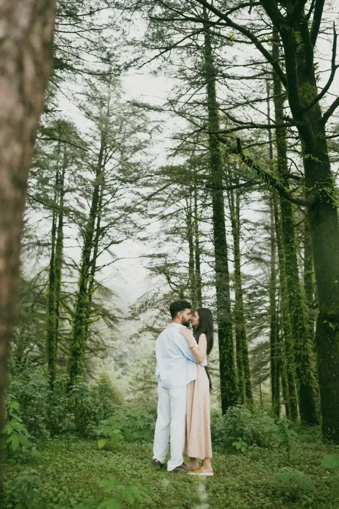 Couple embracing in a peaceful pine forest surrounded by tall trees and natural greenery