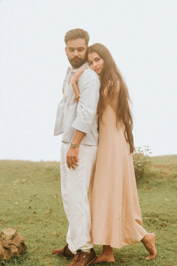 Romantic outdoor portrait of a couple sharing a warm embrace in an open meadow with soft natural light
