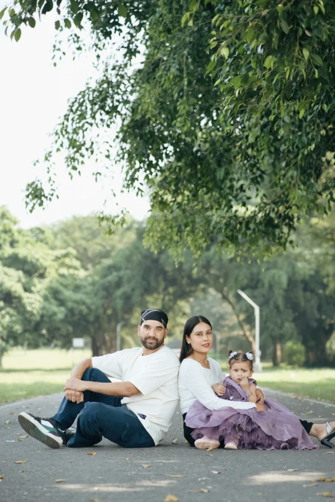 Family sitting together on a peaceful tree-lined road with their little daughter.