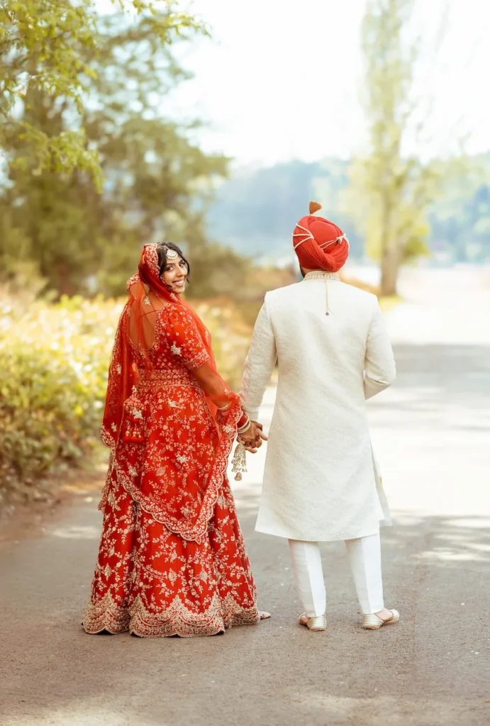 Newlywed Punjabi couple walking together on a scenic road during their wedding celebration in Rishikesh.
