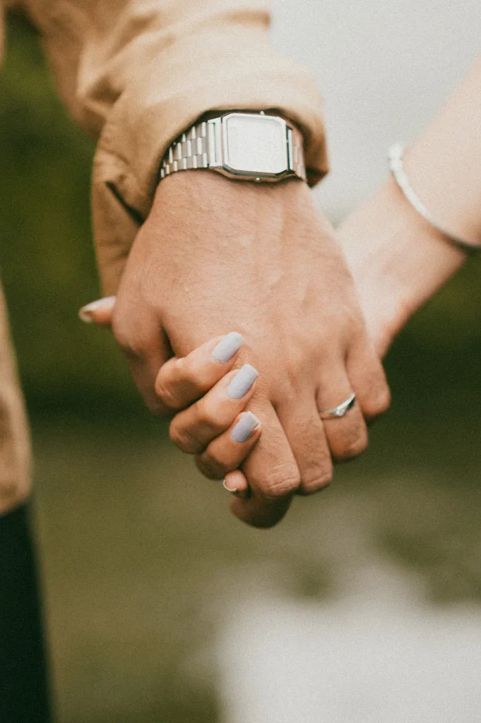 Close-up of a couple holding hands with engagement ring details during an outdoor photoshoot