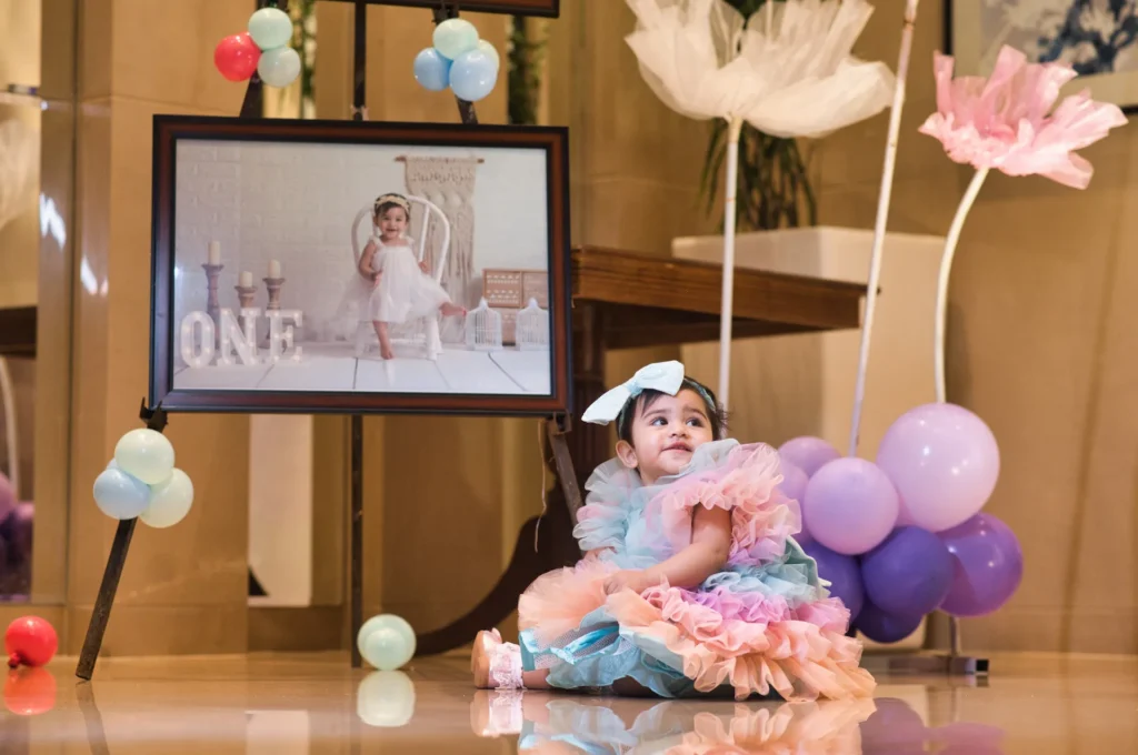Kids Photoshoots in Dehradun featuring a joyful baby celebrating a themed birthday with colorful balloon decorations and a personalized backdrop.