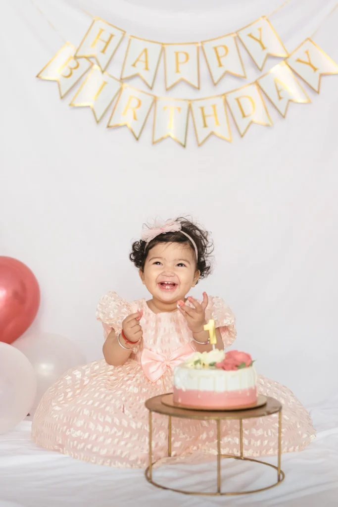 Kids Photoshoots in Dehradun capturing a smiling baby celebrating a first birthday with cake, balloons, and a Happy Birthday backdrop.