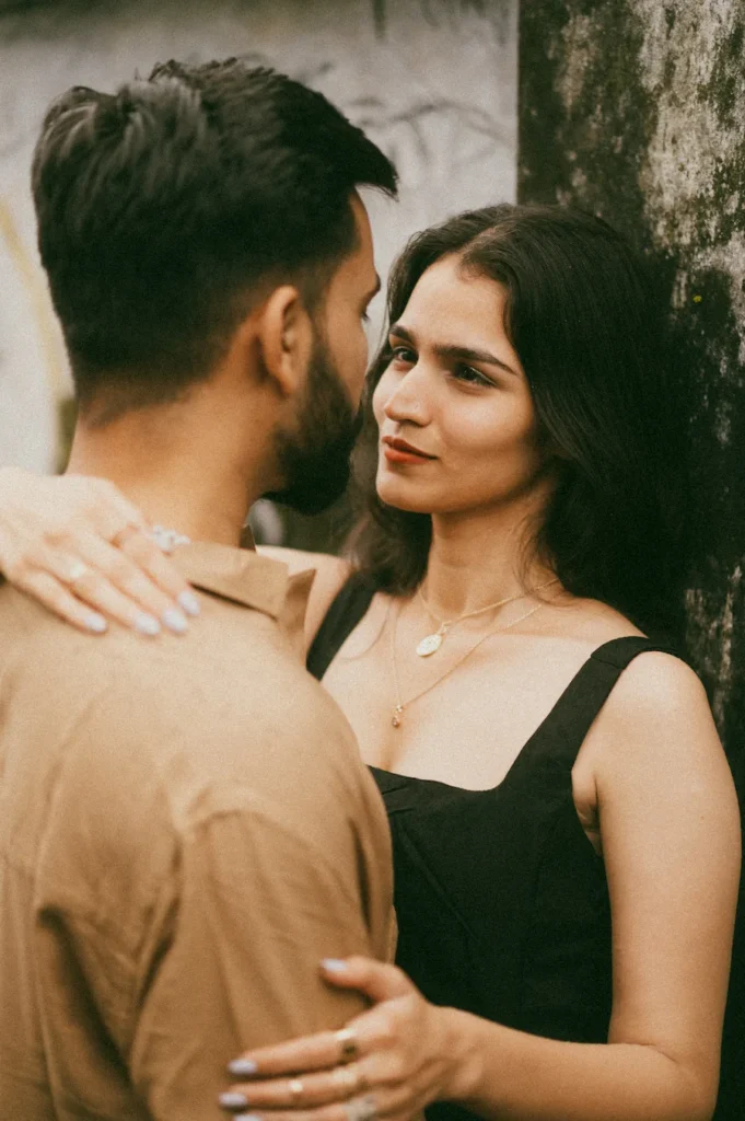 Couple sharing a heartfelt gaze beside a rustic wall during a natural outdoor portrait session