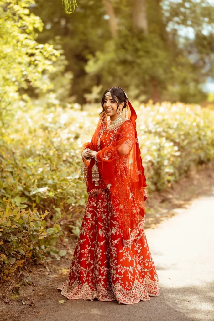 Punjabi wedding in Rishikesh bridal portrait featuring a bride in a red lehenga at an outdoor destination wedding venue