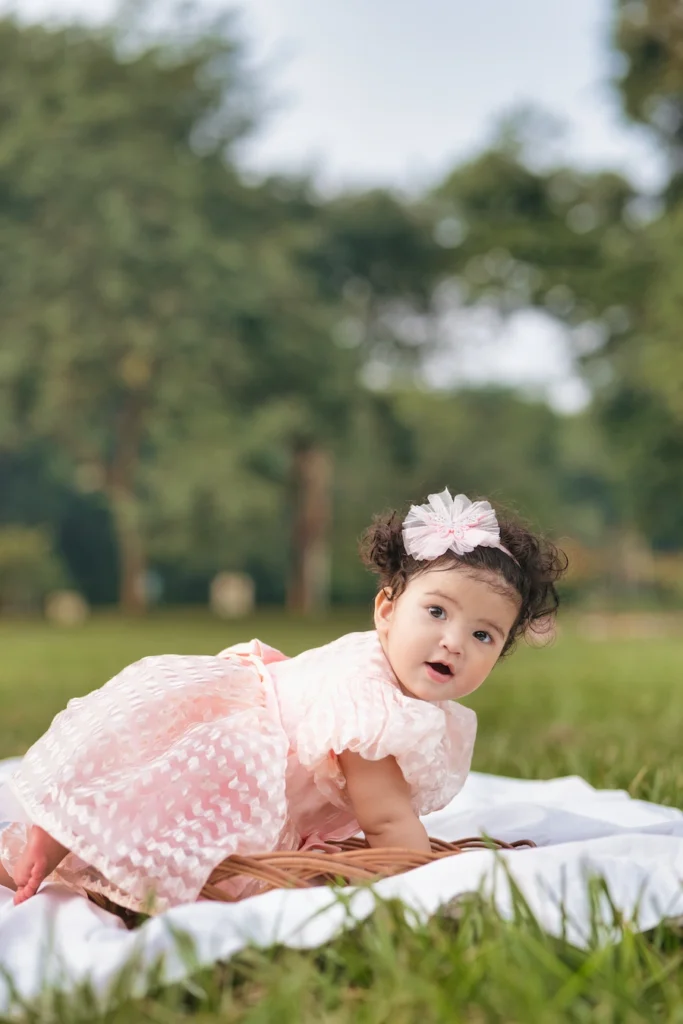 Baby crawling on a blanket in a grassy park during a playful photoshoot.