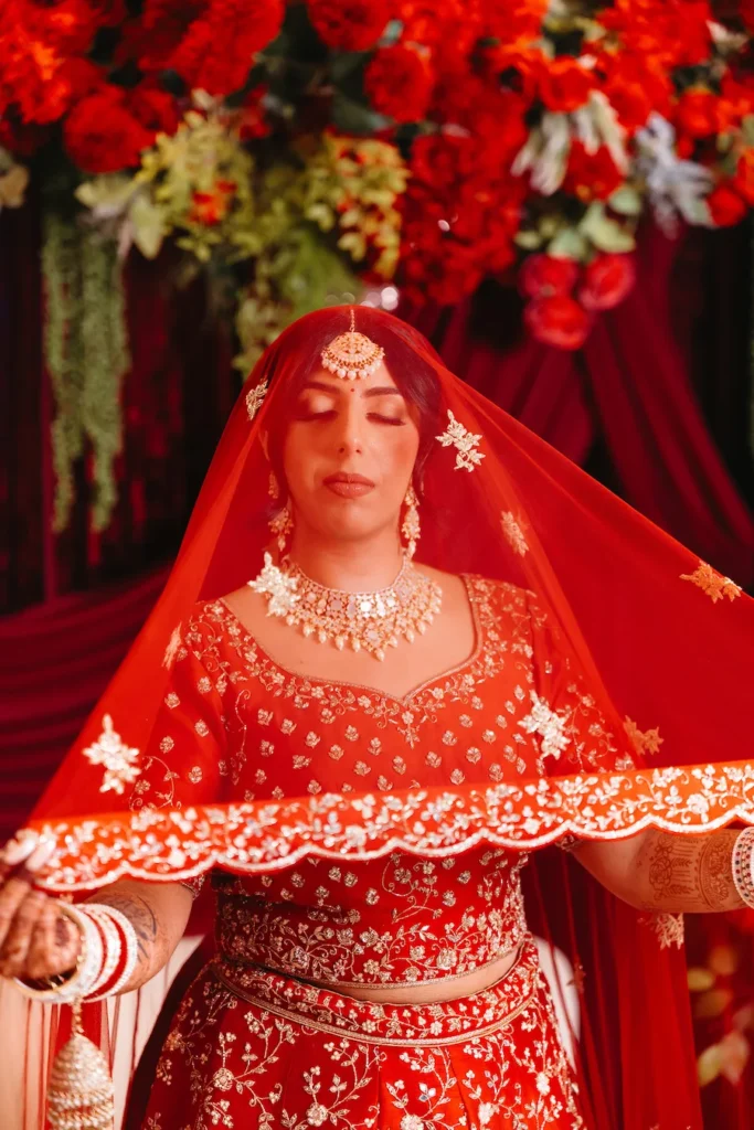 Elegant Punjabi bride in a red bridal lehenga and traditional jewelry at an intimate wedding in Rishikesh.
