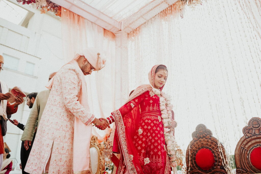 Bride and groom holding hands during the wedding ceremony with elegant floral décor