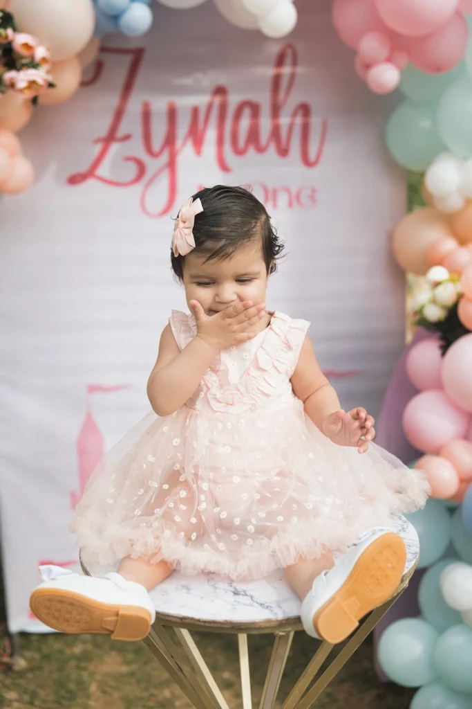 Little girl smiling on a chair during her first birthday celebration.