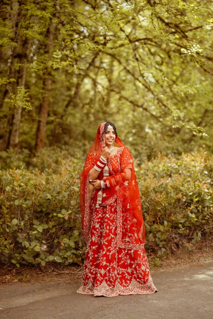 Punjabi wedding in Rishikesh bridal portrait featuring a bride in a red lehenga surrounded by natural greenery