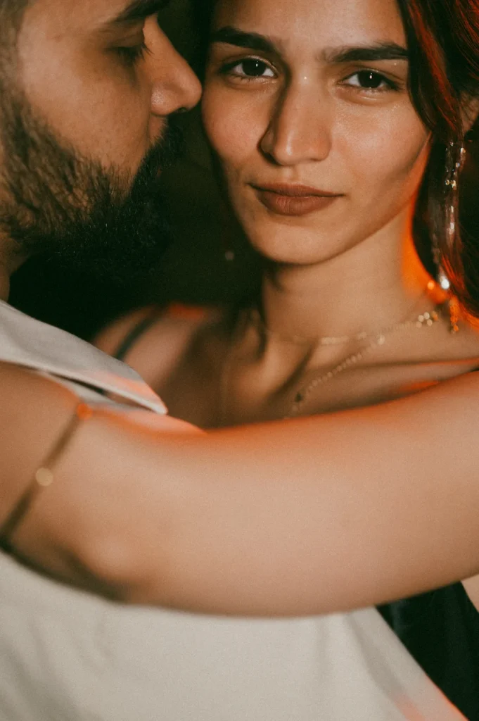 Artistic close-up portrait of a woman embracing her partner with warm cinematic lighting and expressive eyes