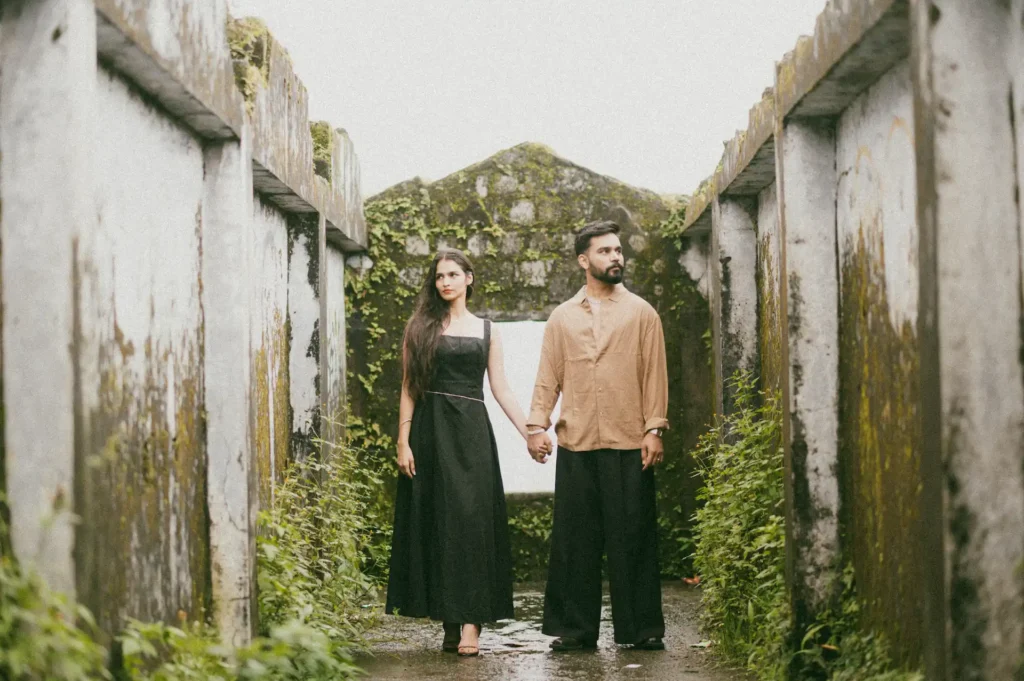 Couple holding hands while standing inside a historic stone structure with rustic architecture and artistic composition