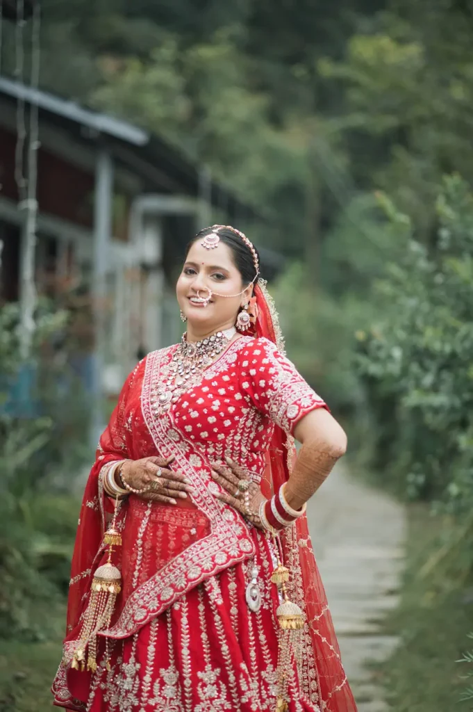 Elegant bridal portrait in a traditional red lehenga captured in natural surroundings.