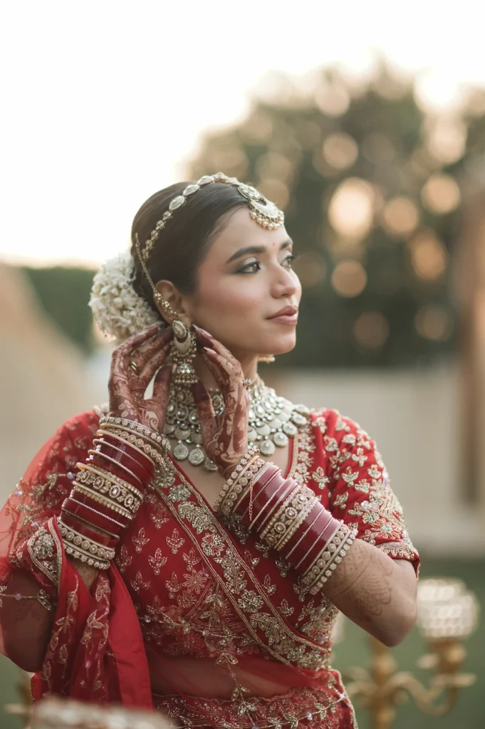 Bride adjusting her earrings during golden hour, showcasing timeless bridal elegance and natural beauty.