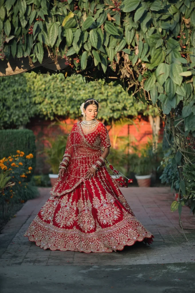 Bridal portrait framed by lush greenery and traditional red wedding attire