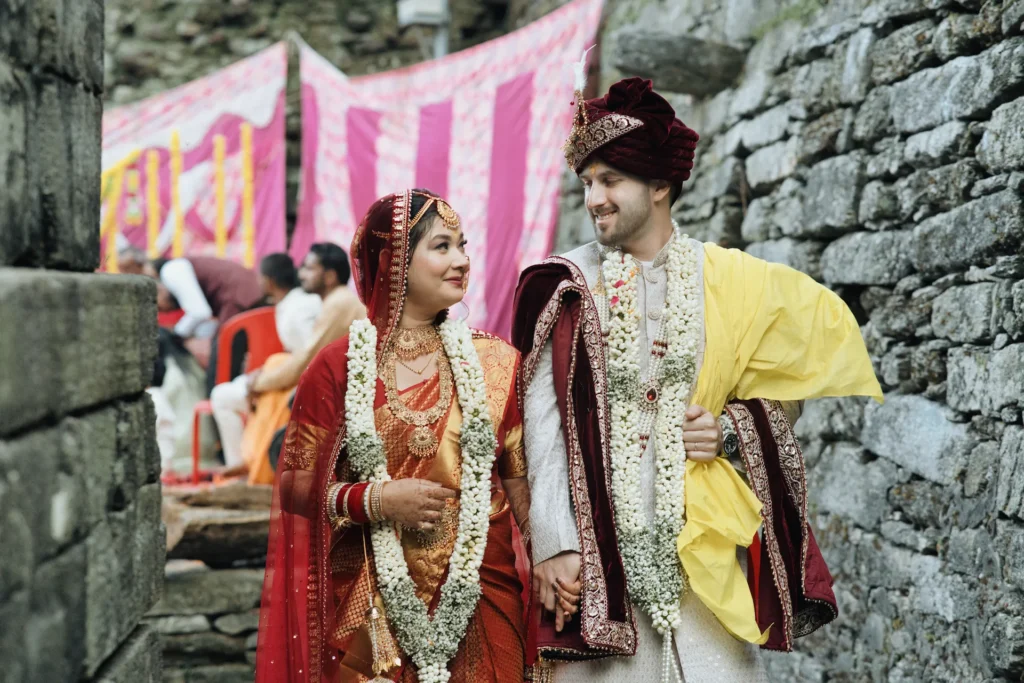 Bride and groom walking near a stone wall temple captured by the best wedding photographers in Dehradun.