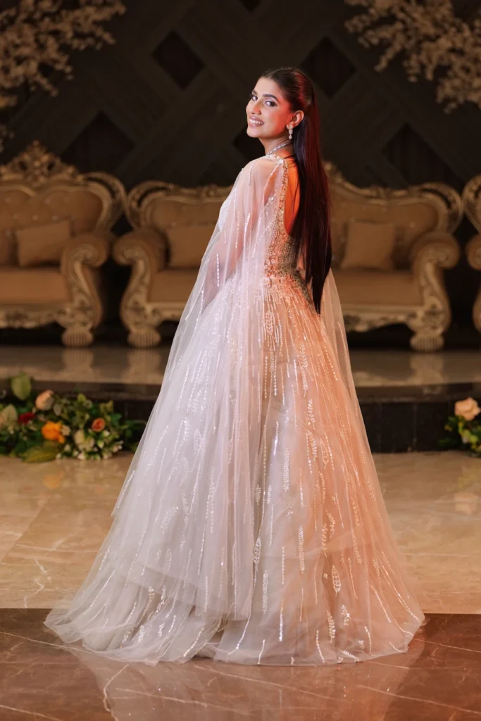 Bride in a sparkling reception gown posing confidently inside a beautifully decorated wedding venue.