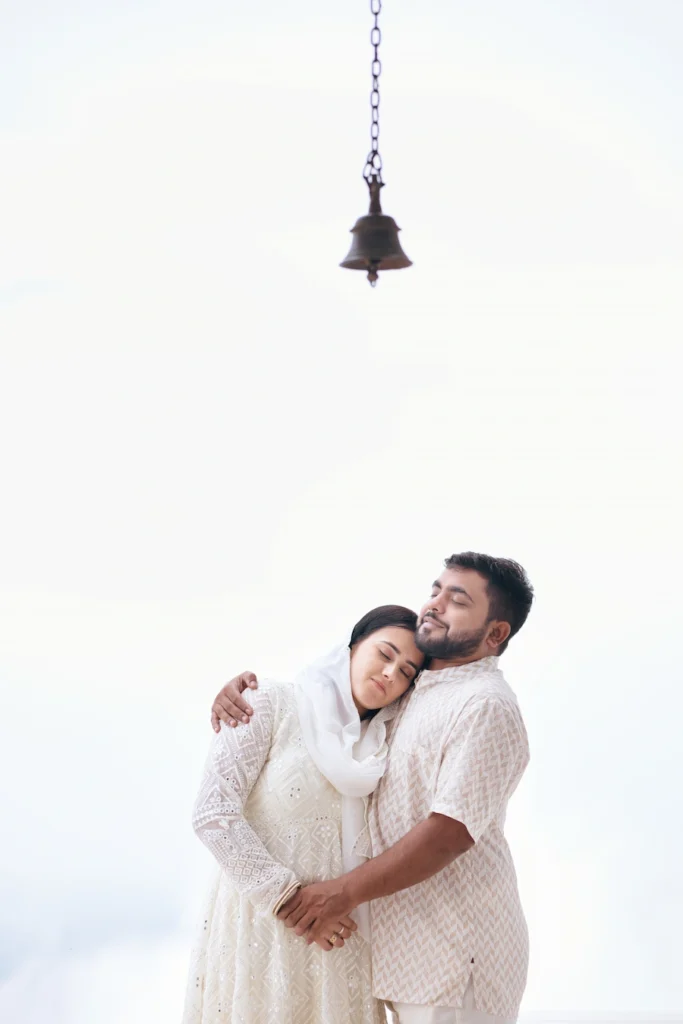Traditional Pahadi Pre-Wedding couple embracing beneath a temple bell in Uttarakhand