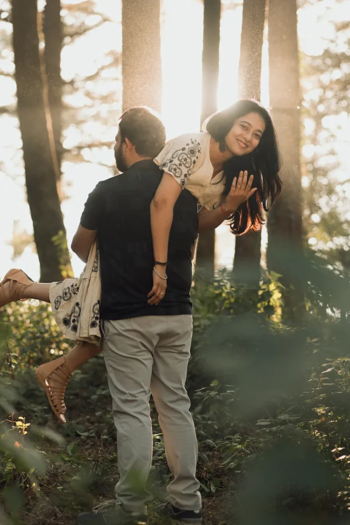 Professional Pre Wedding Photographer in Dehradun documenting a playful couple pose in a pine forest during golden hour.