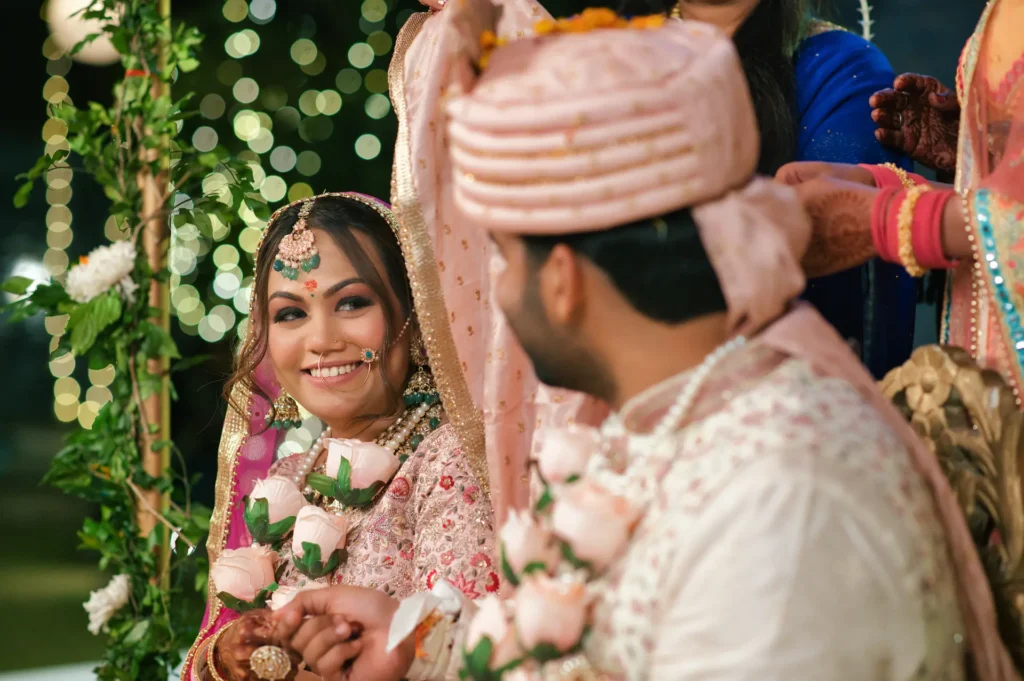Bride smiling at the groom during the wedding ceremony with floral garlands and joyful expressions