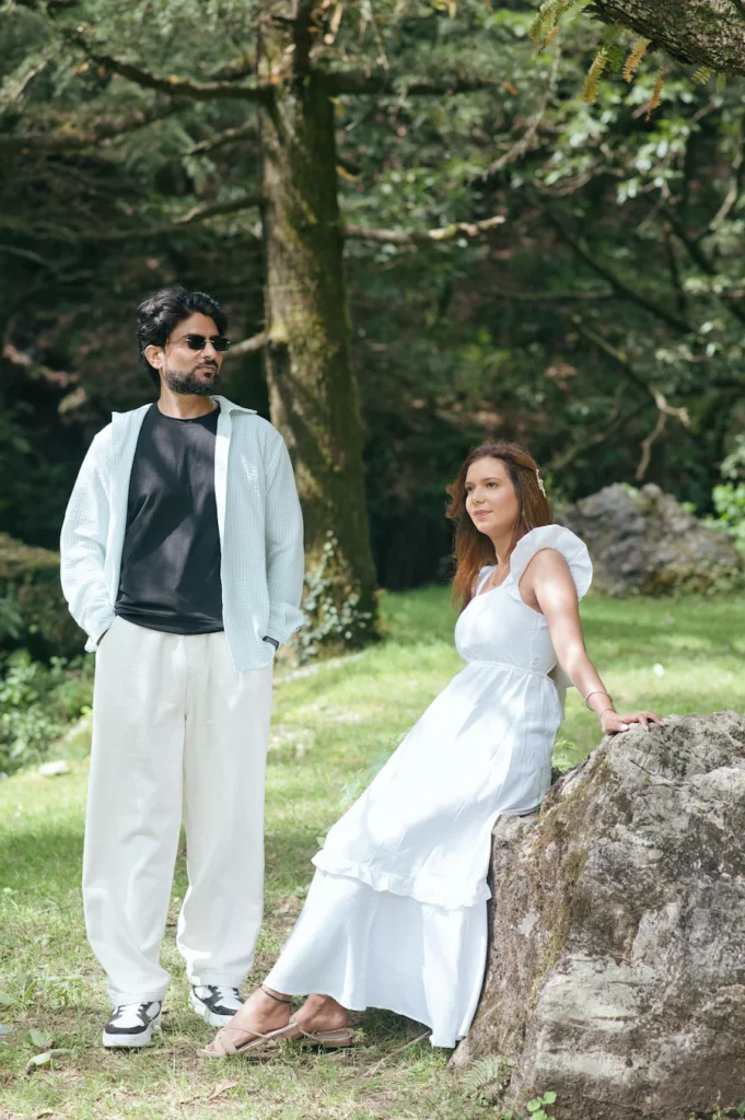 Couple enjoying a relaxed outdoor pre-wedding photoshoot in a lush green forest.