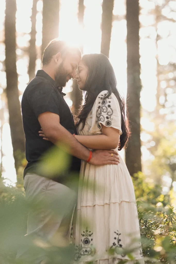 Golden hour pre wedding photography in Dehradun with a couple embracing among tall pine trees.