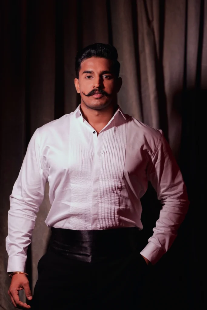 Groom portrait in formal attire with a classic mustache before the wedding ceremony.