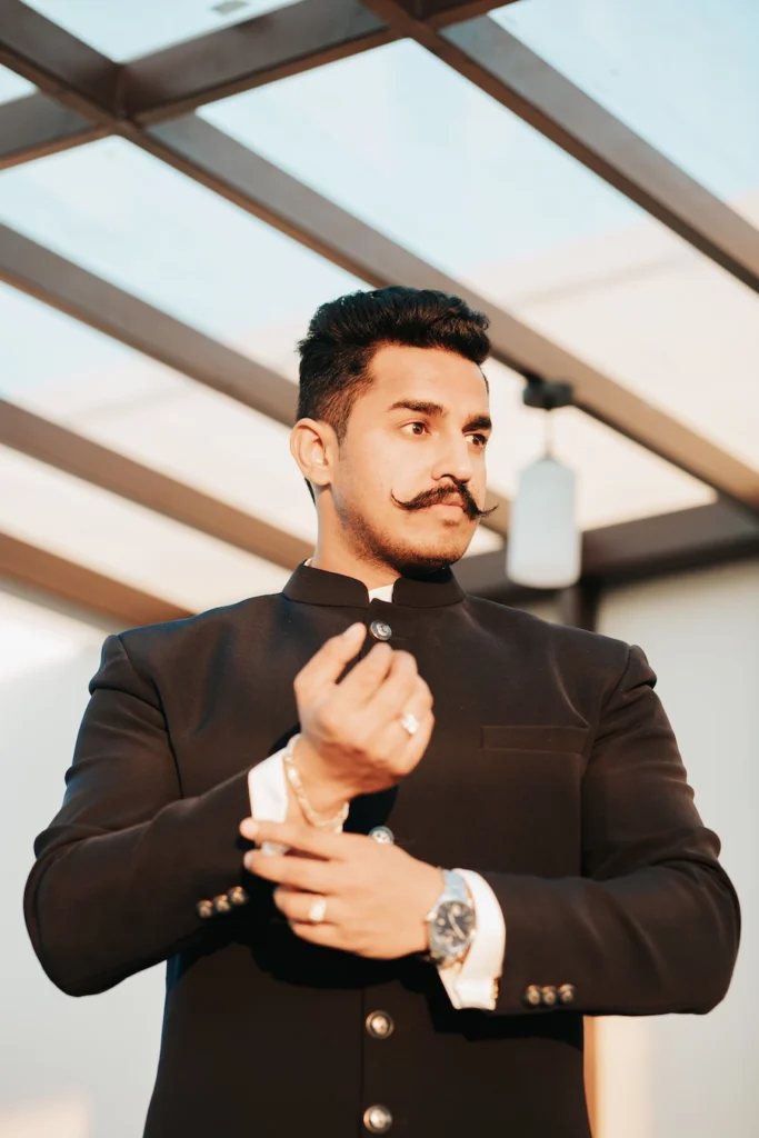 Groom adjusting his sherwani cuff during wedding preparations.