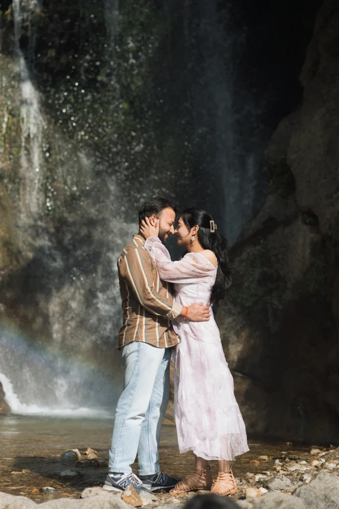 Romantic waterfall pre wedding photoshoot in Uttarakhand featuring a couple sharing a cinematic moment beside cascading falls.
