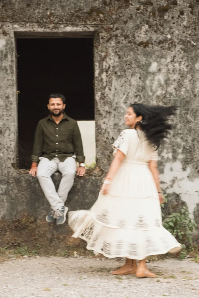 Candid pre wedding photography at a heritage location in Uttarakhand featuring a bride twirling while her partner smiles.