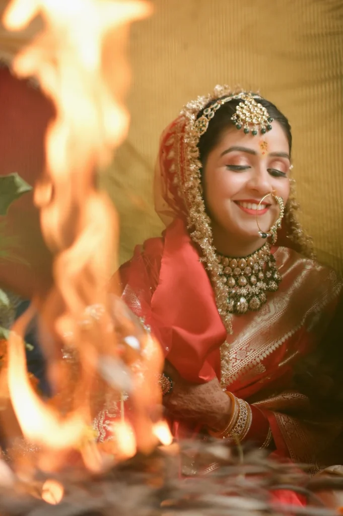 Bride smiling peacefully beside the sacred fire during traditional wedding rituals