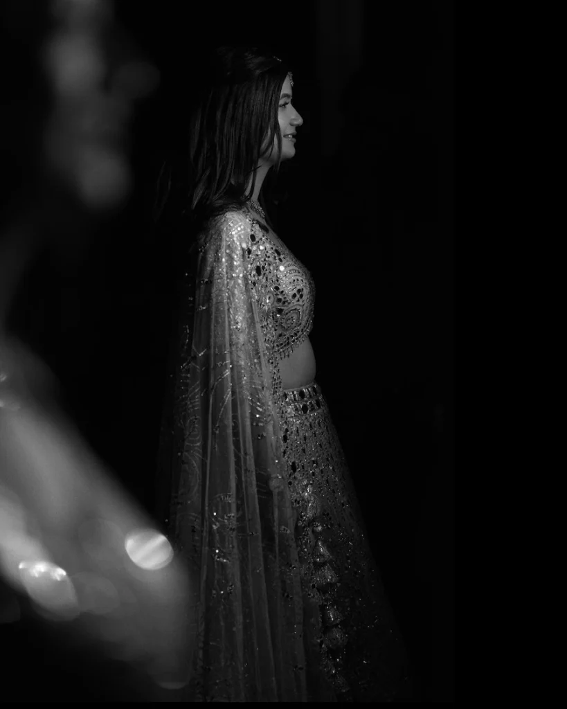 Bride posing in a dramatic low-light portrait wearing an embellished engagement lehenga.