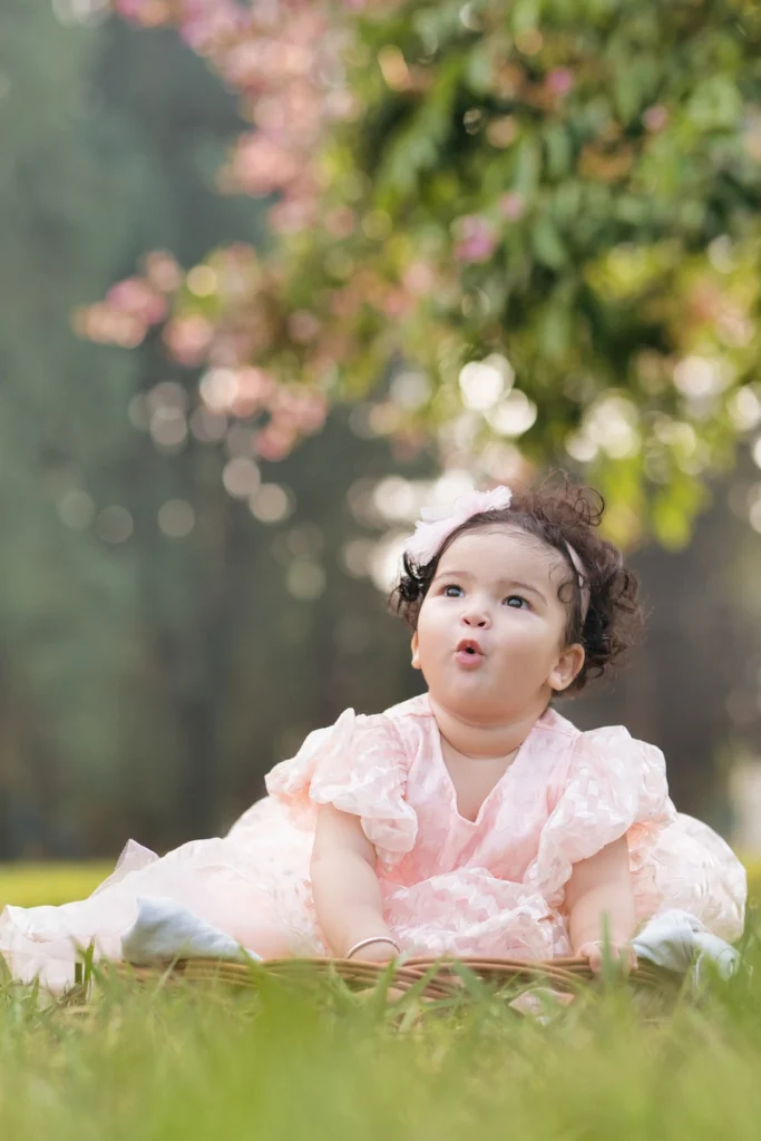 First birthday photoshoot of a baby girl in a pink dress enjoying an outdoor garden portrait session