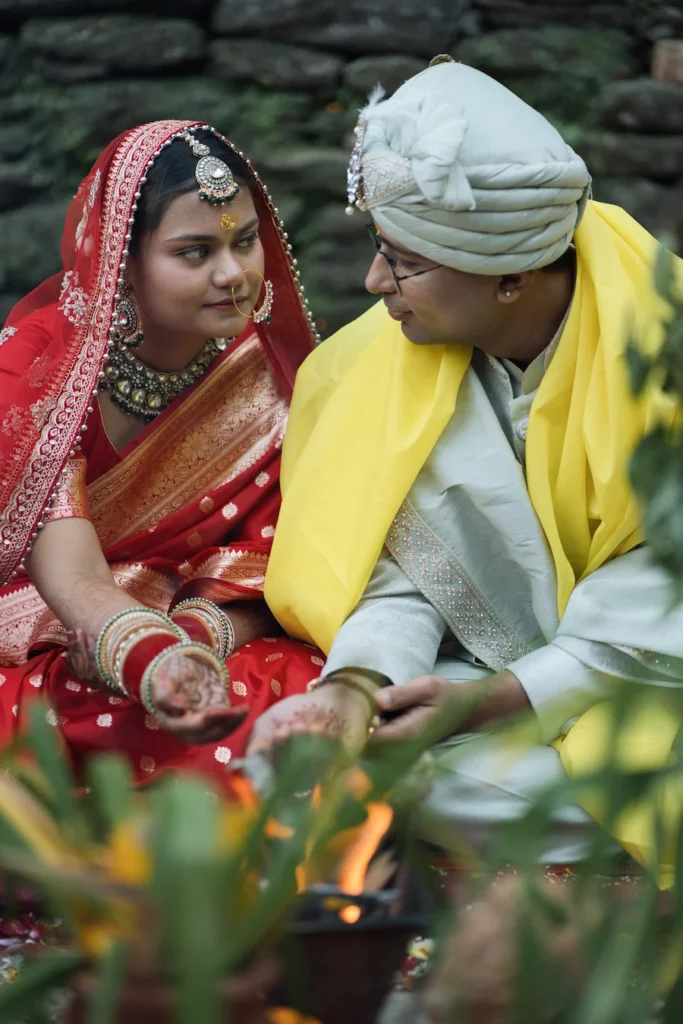 Bride and groom exchanging a heartfelt glance during a sacred fire ritual.