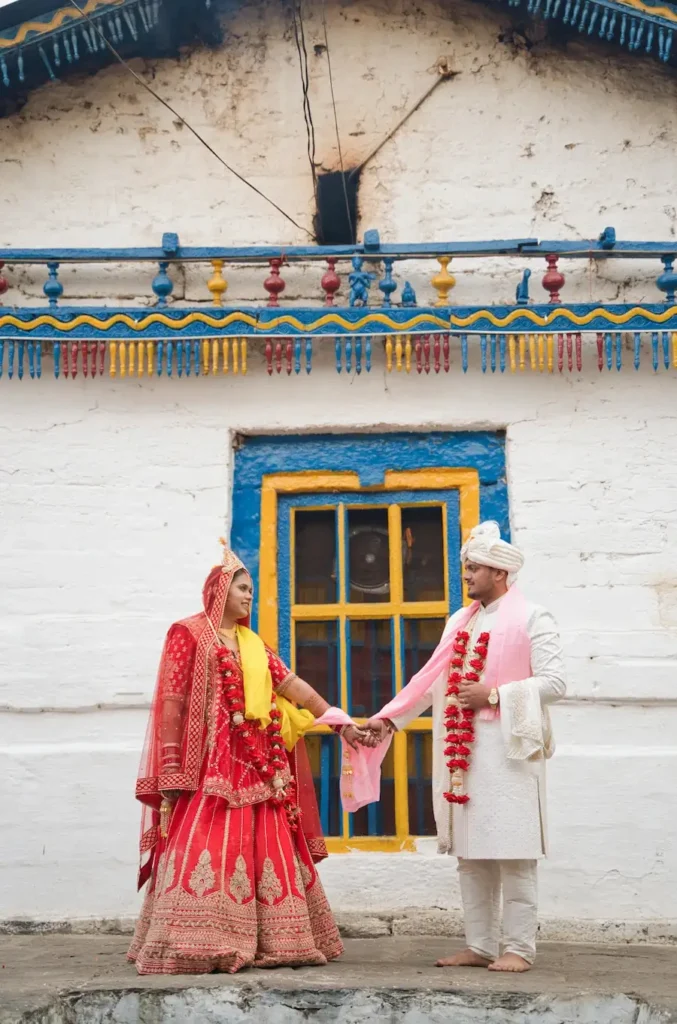 Newly married couple holding hands in front of the historic Triyuginarayan Temple.