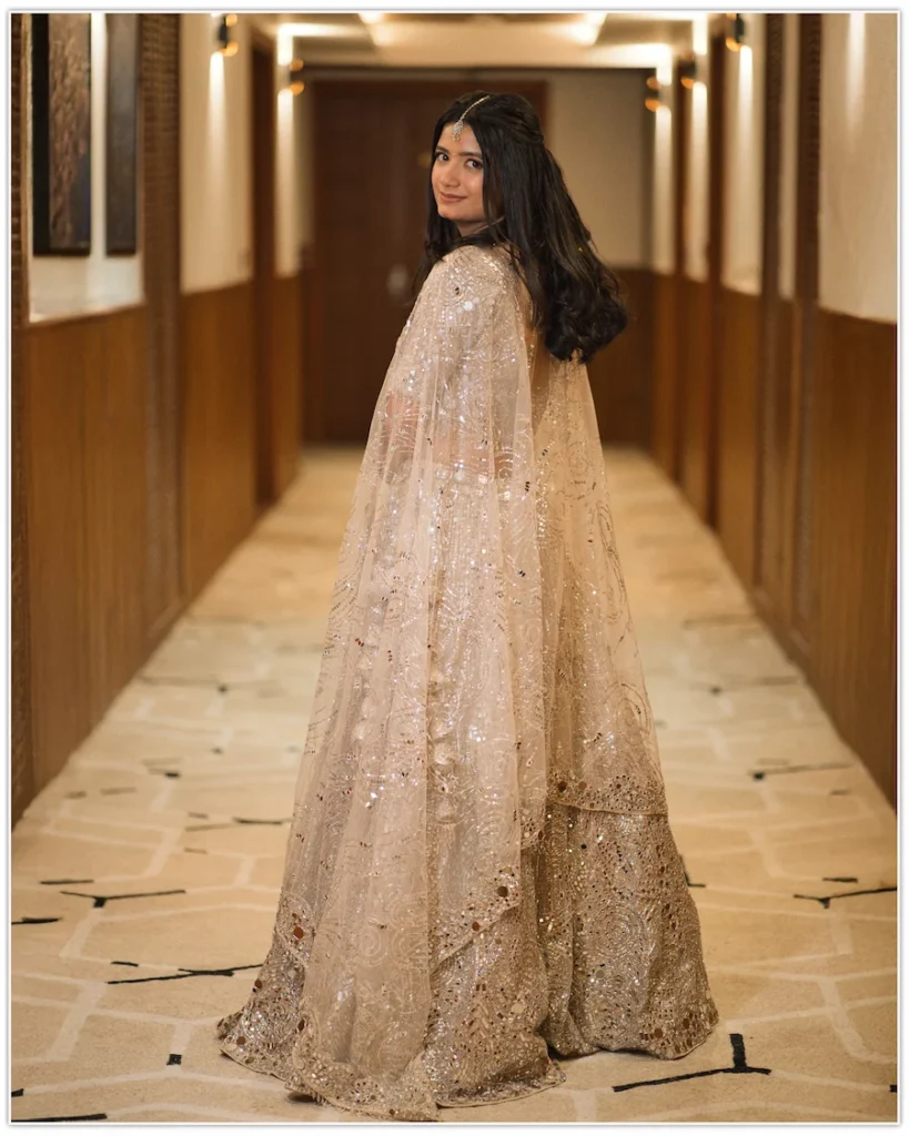 Bride looking back while walking through a beautifully lit hotel corridor.