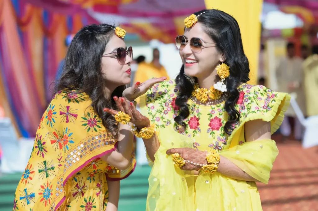 Bride and friend sharing a joyful moment during the colorful Haldi ceremony.