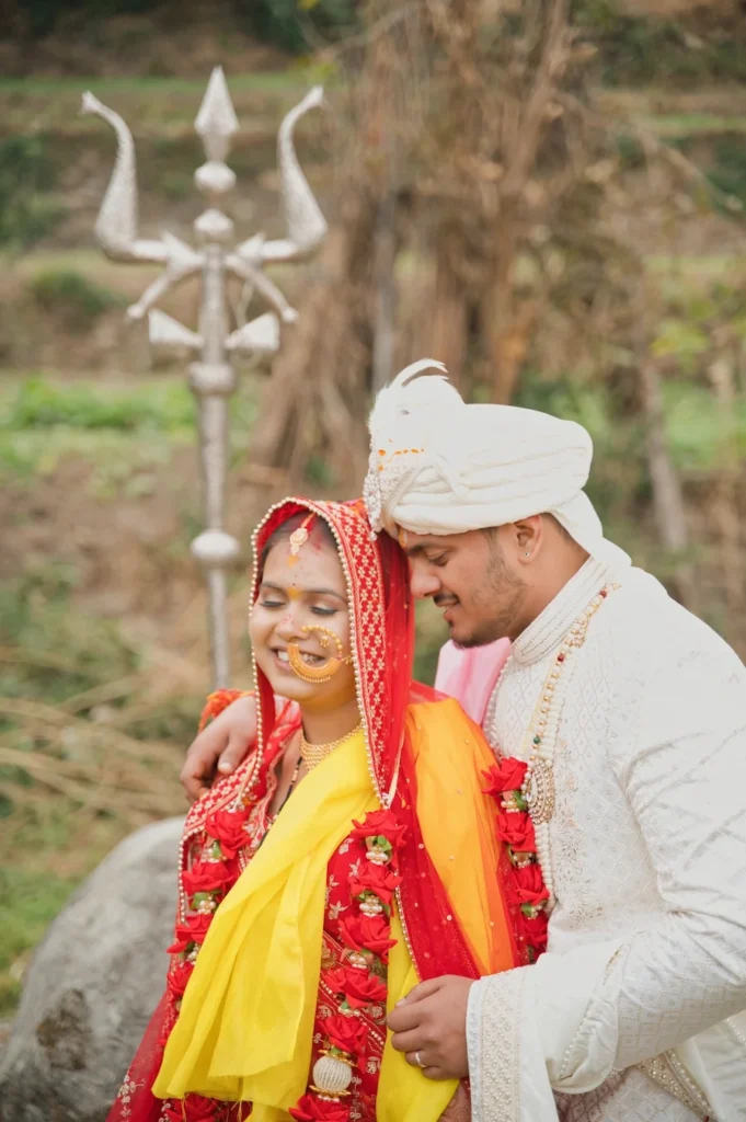 Bride and groom sharing a romantic embrace beside the sacred Trishul at Triyuginarayan Temple.
