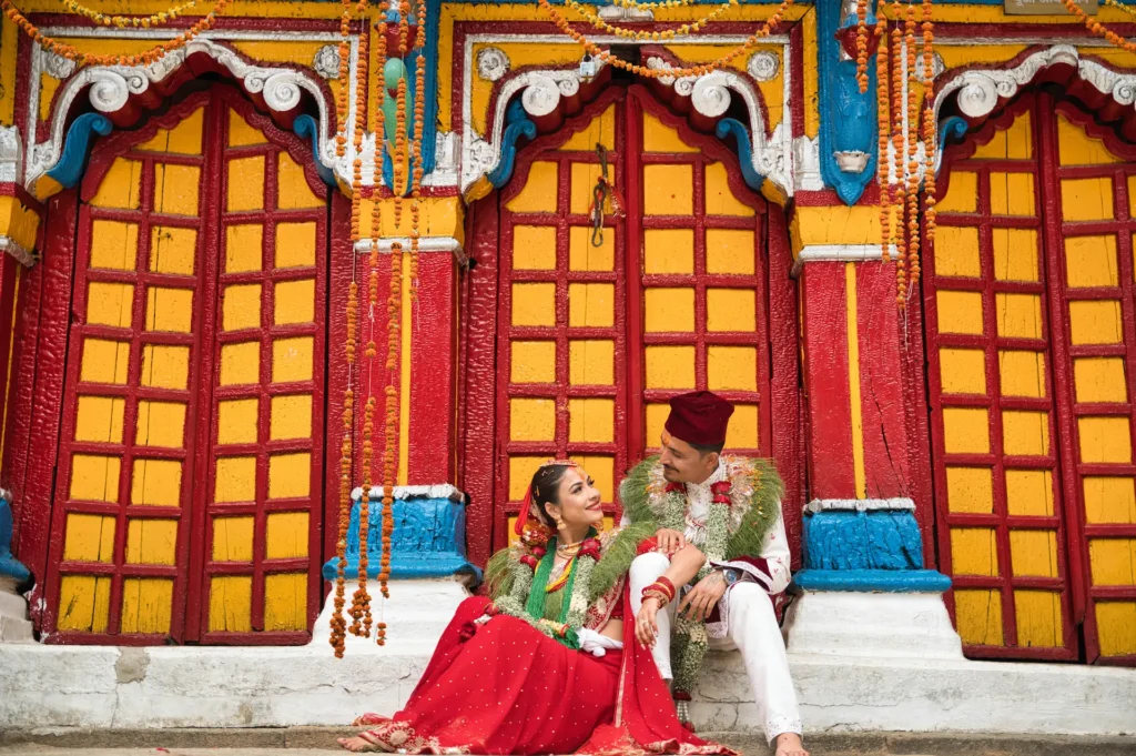 Traditional Ukhimath wedding couple portrait captured outside Omkareshwar Temple, showcasing vibrant Himalayan temple architecture and authentic Uttarakhand wedding traditions.
