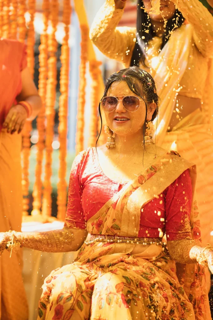 Bride enjoying vibrant haldi celebration surrounded by flower petals and festive rituals